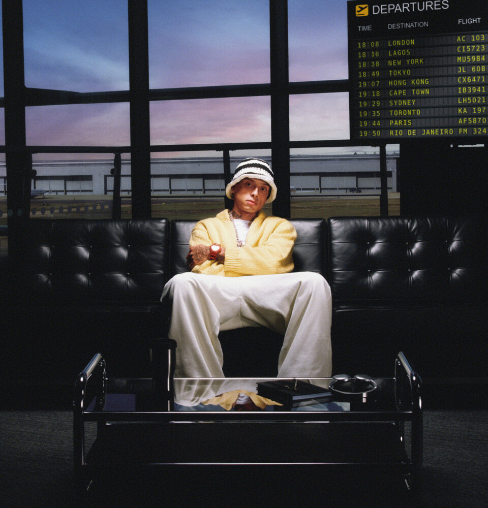 Rapper Central Cee sitzt auf einem Sofa und trägt eine Uhr von G-Shock