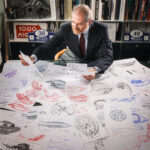 Mann sitzt am Schreibtisch, auf dem Zeichnungen der Serpenti von Bulgari liegen