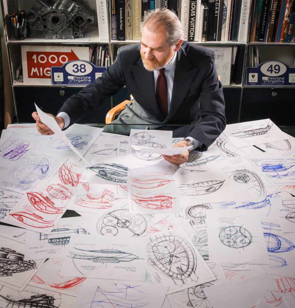 Mann sitzt am Schreibtisch, auf dem Zeichnungen der Serpenti von Bulgari liegen