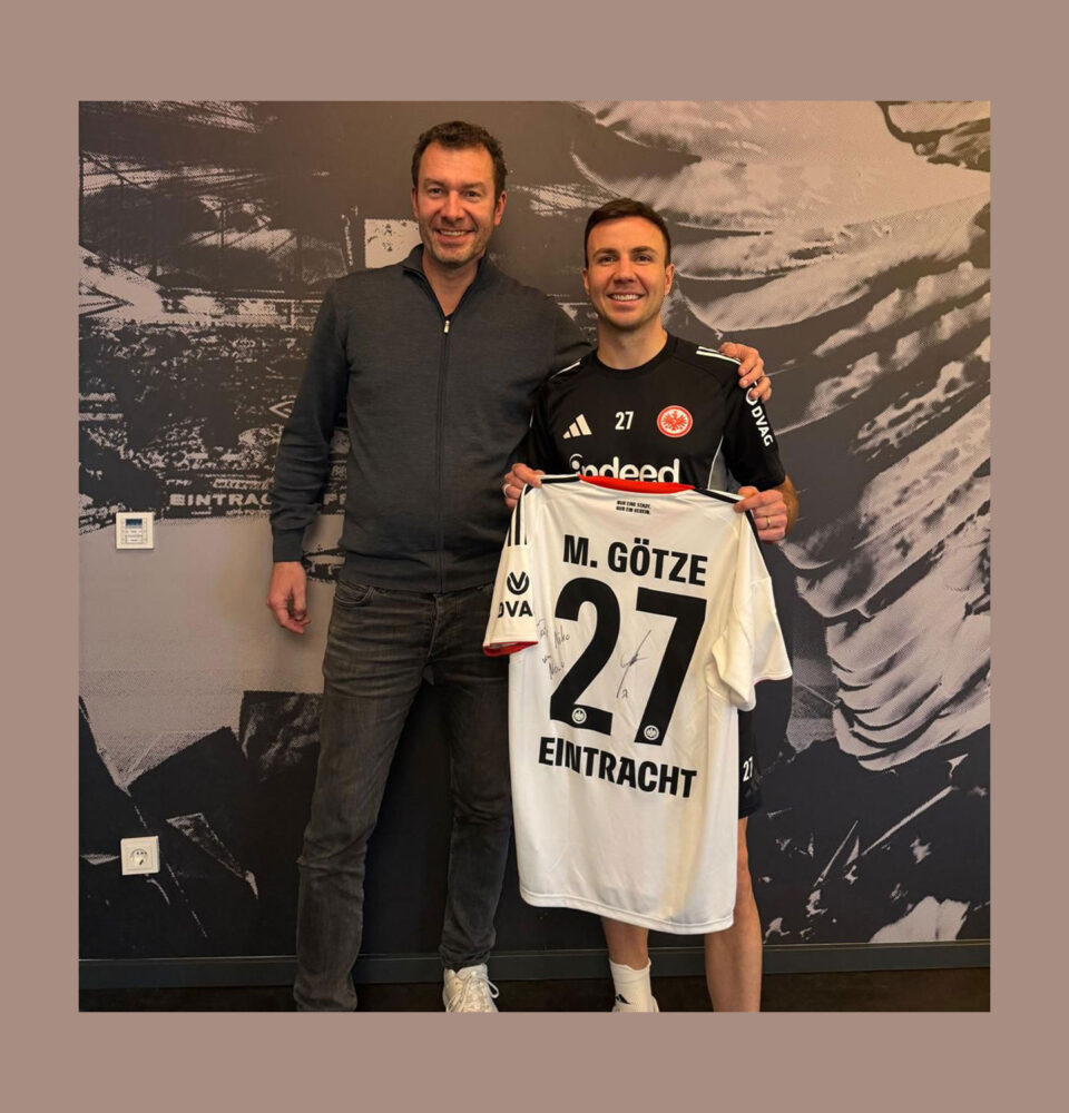 Tim Stracke und Mario Götze stehen nebeneinander, Mario Götze hält ein Trikot mit der Nummer 27